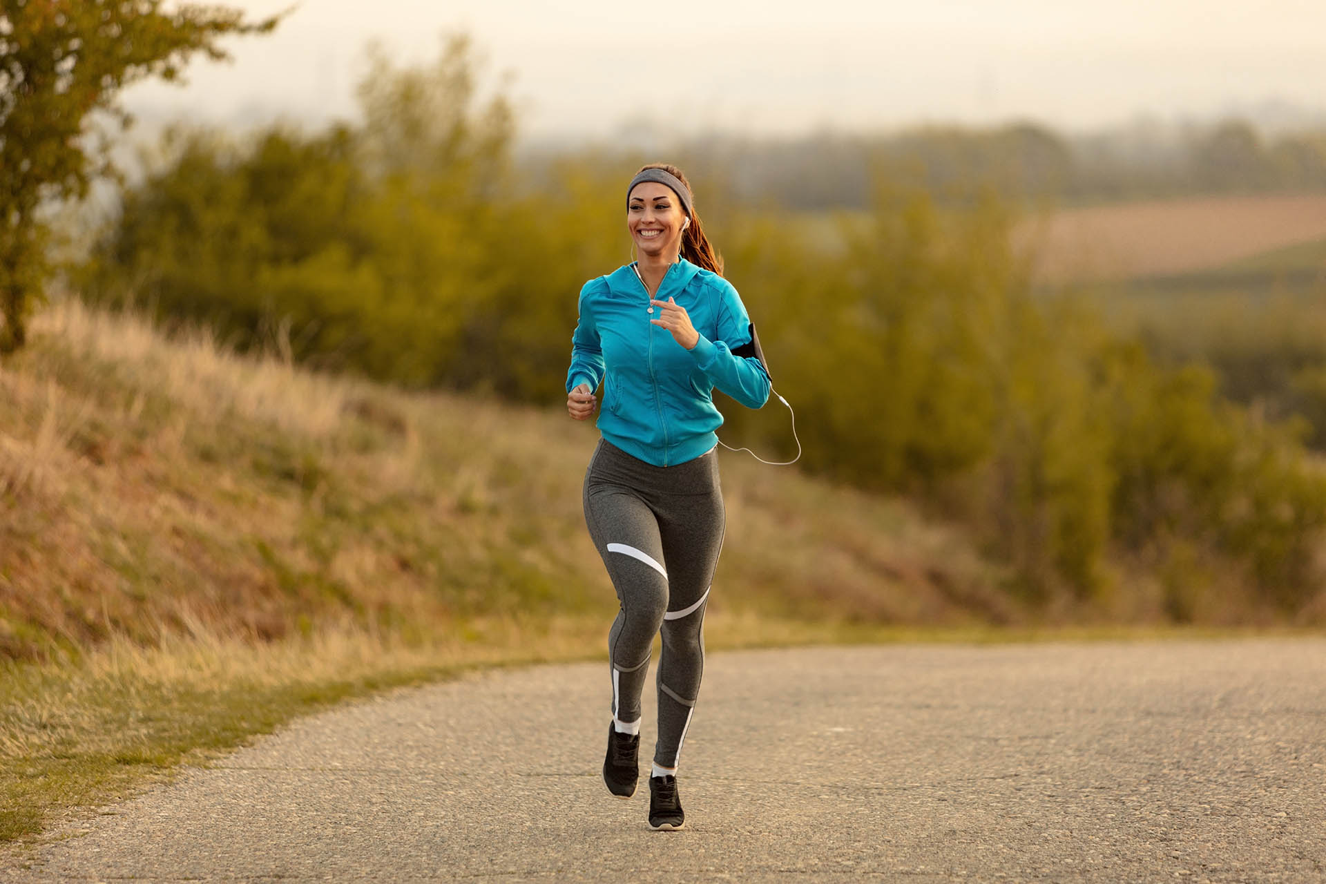 Happy female athlete road running in the morning.